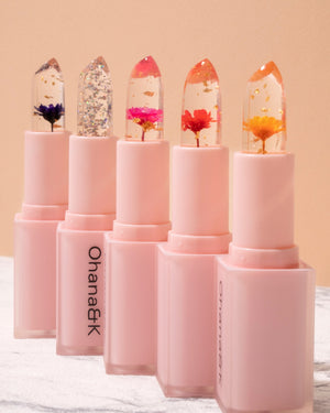 All five variations of Ohana&K Lip Balm, featuring real flowers or glitter, delivering a custom pink tint with a hydrating formula.